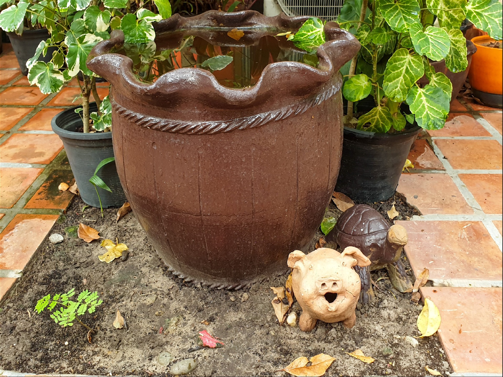 Керамические ваза и статуэтки свинки под ней в саду