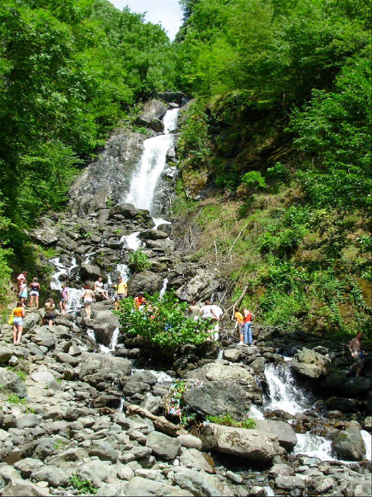 туристы стоят у подножия молочного водопада