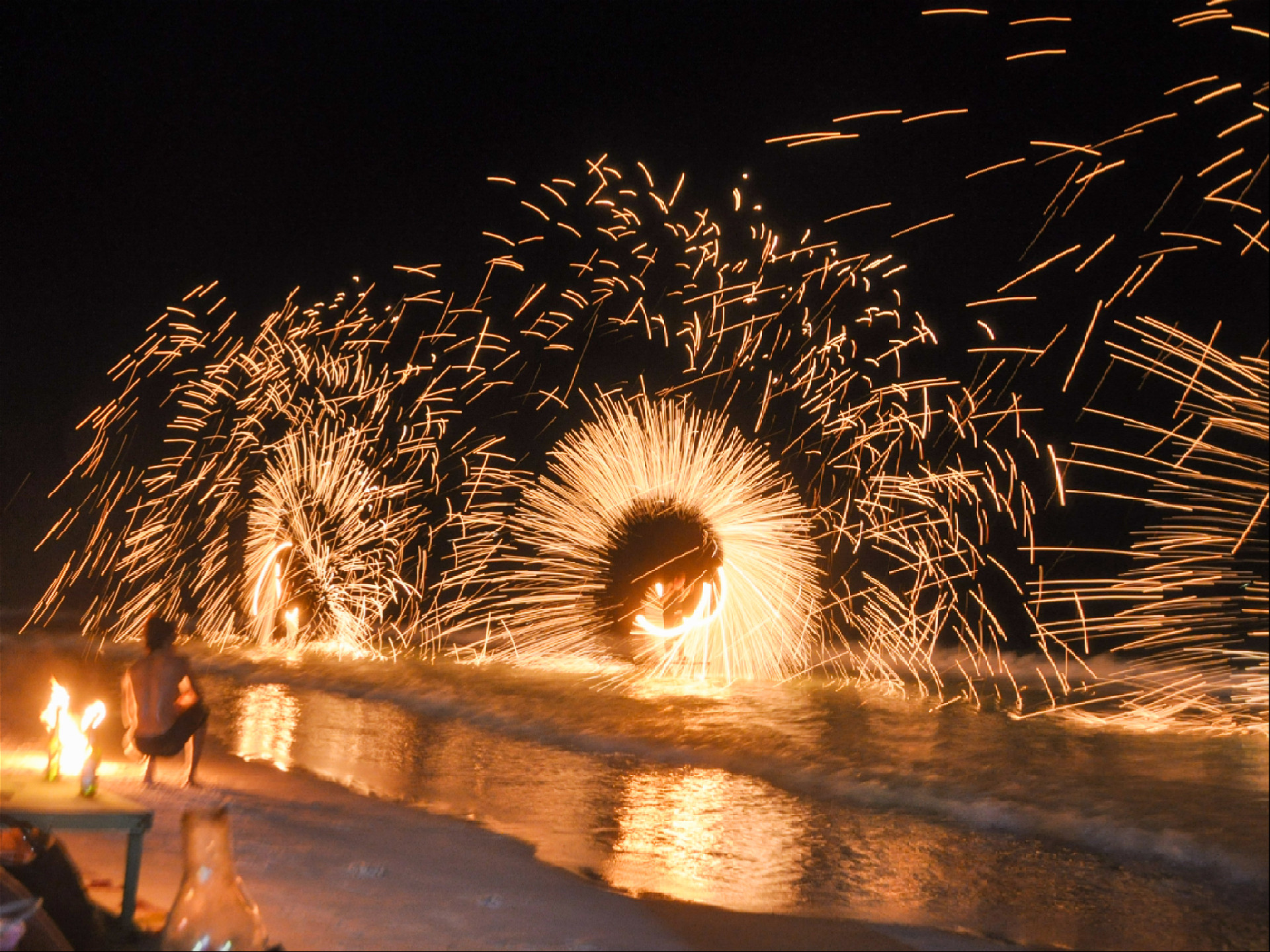 вращение огненных колес над водой на пляже