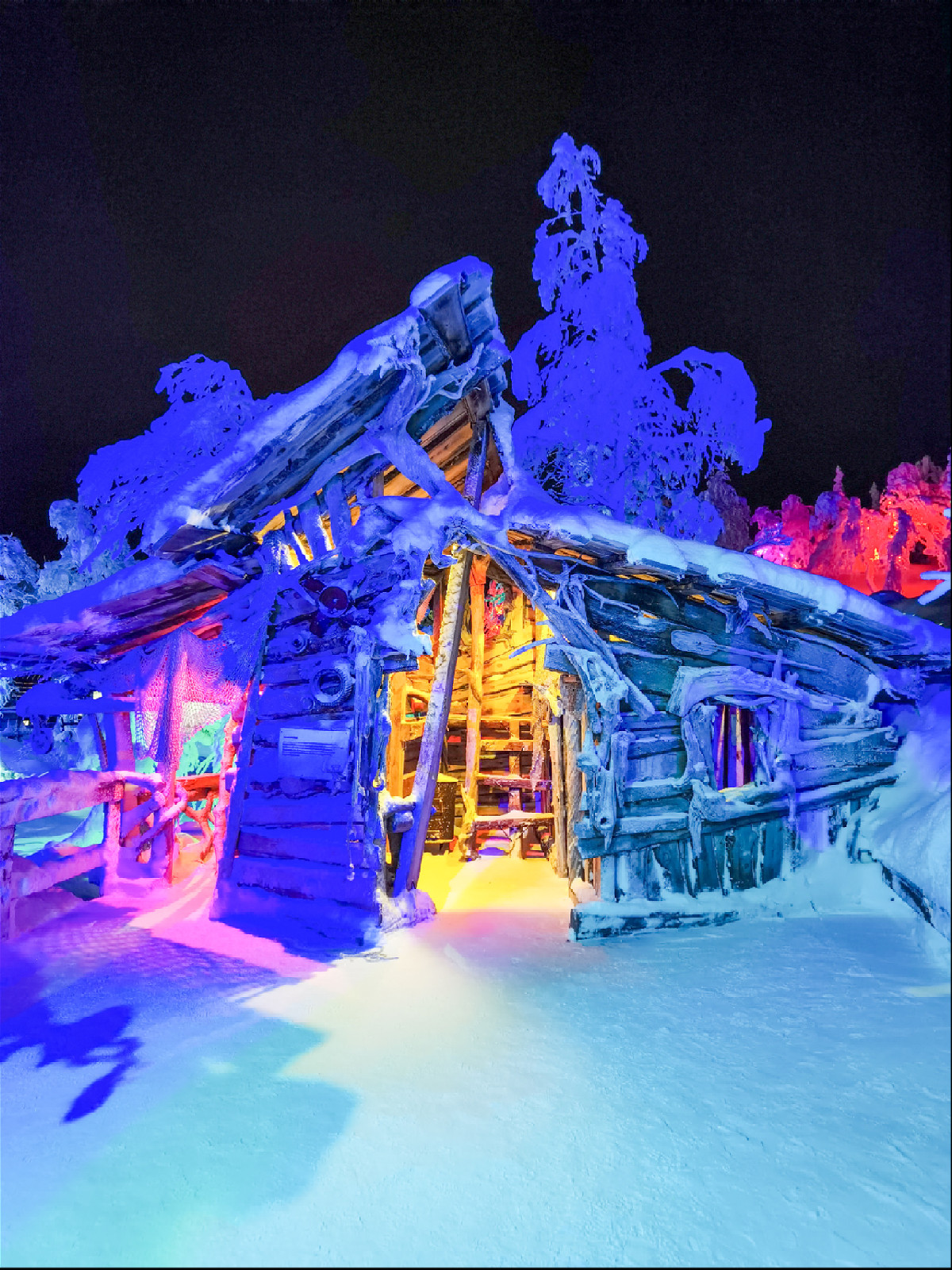 деревянный дом с разноцветной подсветкой в зимнем лесу