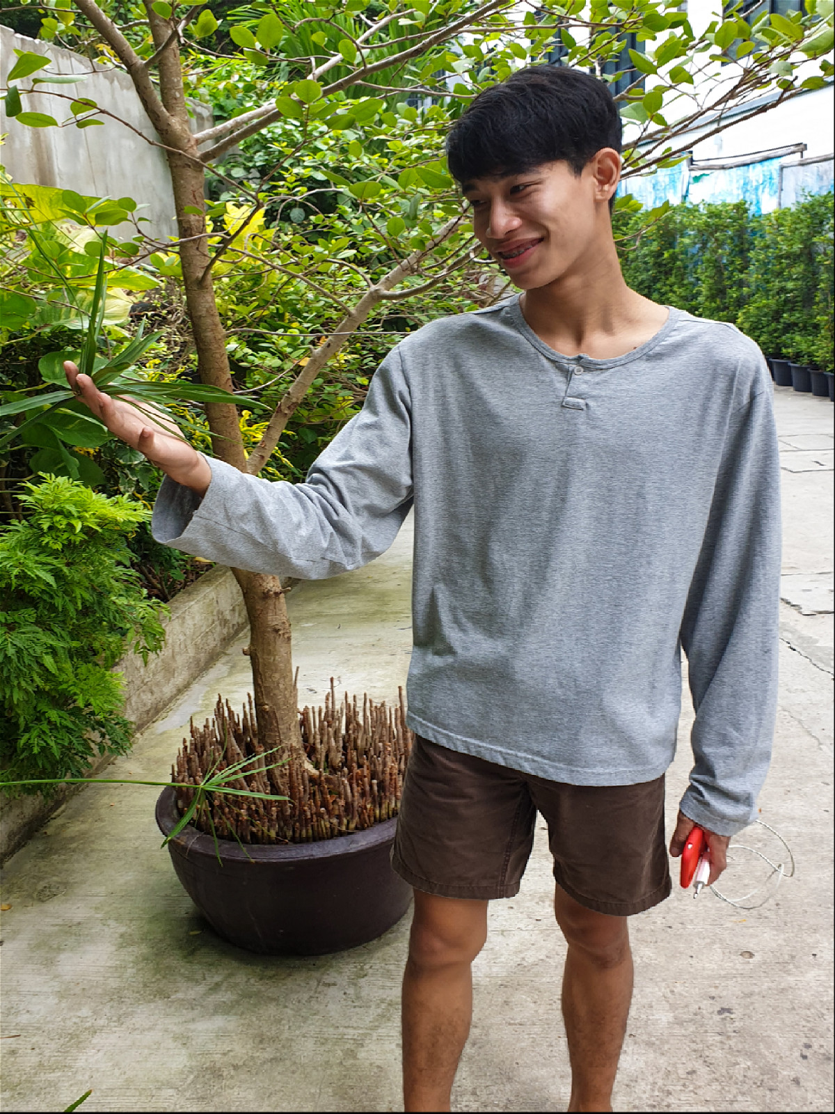 молодой таец любуется растением в саду